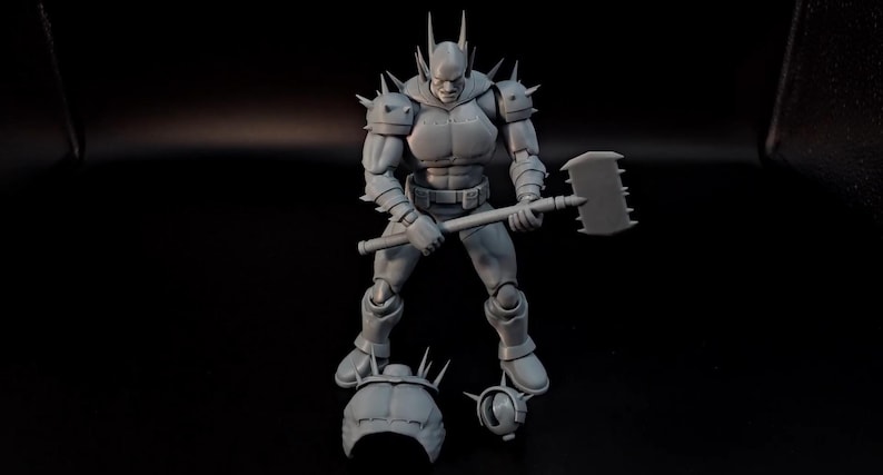 May include: A grey unpainted action figure of a muscular character with spiked shoulder armour and a headpiece with tall spikes. The figure holds a large rectangular hammer with a serrated edge. Two additional head pieces are placed at the feet.