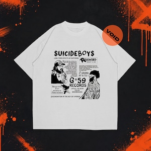 Può includere: Una t-shirt bianca a maniche corte con una stampa grafica nera sul petto. Il design include il testo $UICIDEBOY$, G*59 RECORDS e vari testi e illustrazioni, tra cui una persona con un microfono e una figura tatuata.