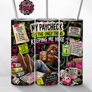 May include: A cylindrical stainless steel tumbler with a metal straw, featuring a black background and colorful graphic illustrations. The design includes text such as MY PAYCHECK IS THE ONLY THING KEEPING ME HERE, along with various office-themed notes, a person sitting at a desk, a piggy bank, and a medical IV bag labeled PAYCHECK LIFE SUPPORT.