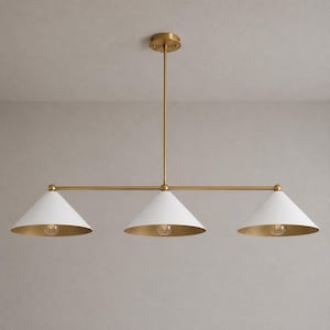 May include: A linear chandelier featuring a central brass rod and three white conical shades. Each shade has a gold-toned interior and a single exposed light bulb. The fixture is suspended from a matching brass ceiling canopy by a vertical rod.