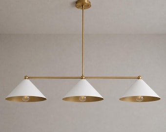 May include: A linear chandelier featuring a central brass rod and three white conical shades. Each shade has a gold-toned interior and a single exposed light bulb. The fixture is suspended from a matching brass ceiling canopy by a vertical rod.