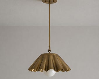 May include: A brass pendant light featuring a wide, ruffled, bell-shaped shade suspended from a thin vertical rod and a circular ceiling canopy. A single, spherical white glass bulb is positioned at the center of the metallic shade.