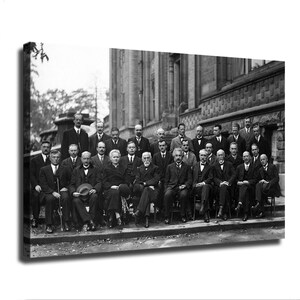 May include: A black and white photograph on canvas showing a large group of scientists posing in front of a building. The group comprises many individuals wearing formal suits and ties, with one woman seated in the centre of the front row.