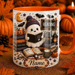 May include: A white ceramic mug with an orange interior and handle, featuring a ghost wearing a purple beanie reading a book titled Spooky Stories. The design includes stacks of books, a black cat, a lantern, pumpkins, bats, and a sign that says READING. A customizable name plate is at the bottom.