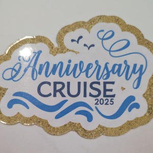 Puede incluir: Una pegatina blanca con un borde dorado brillante, con las palabras "Anniversary Cruise 2025" en azul. Tambi&eacute;n se incluyen gr&aacute;ficos de olas y p&aacute;jaros azules.