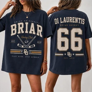 May include: A dark navy blue short-sleeve t-shirt featuring a front graphic with the text BRIAR UNIVERSITY BRIAR Hockey Club EST 2015 and crossed hockey sticks. The back displays the text DI LAURENTIS BRIAR HOCKEY with the large number 66.