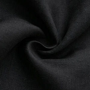 May include: A solid black fabric with a visible woven texture. The material is gathered into a central swirl, creating deep shadows and highlights that emphasize the weave and the matte finish of the dark textile surface in this view.