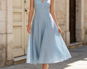 May include: A light blue sleeveless midi dress featuring a V-neckline, a fitted bodice with vertical seam detailing, a defined waistline, and a flared skirt that falls below the knees. The fabric has a visible woven texture throughout the garment.