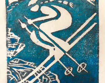 May include: A blue and white linocut print of a skier going downhill with the word "TAHOE" at the top. The print is signed "Alison" and "Downhill Stier" in the bottom right corner.