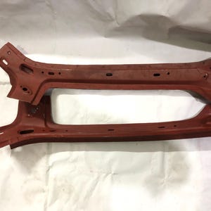 Peut inclure: Deux piliers structurels automobiles allongés de couleur rouille en métal. Chaque pièce présente un design incurvé et effilé avec de multiples trous de montage et fentes pré-percés sur toute la longueur, montrant une surface industrielle brute.