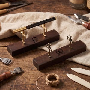 May include: Two rectangular dark wood pen stands featuring ornate brass-colored metal supports. One stand is engraved with the letter D and the name Daphne, while the other features a shield emblem with the letter B and the name Brayden.