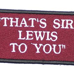 May include: A rectangular embroidered patch with a deep maroon background and a thick black border. The text "THAT'S SIR LEWIS TO YOU" is stitched in white capital letters across the center of the patch, featuring a clear and bold font style.
