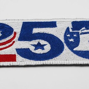 May include: A rectangular embroidered patch featuring the number 250 in blue thread. The number 2 is accented with red stripes, the 5 contains a blue star, and the 0 is shaped like a blue Liberty Bell with white stars and a red accent.