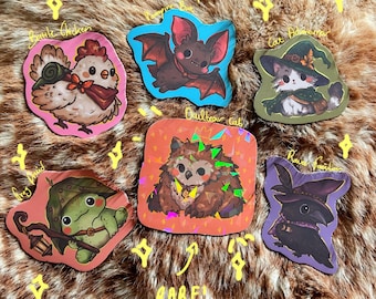May include: A collection of six die-cut stickers featuring illustrated characters: a chicken labeled Battle Chicken, a bat labeled Vampire Bat, a cat labeled Cat Adventurer, a frog labeled Frog Druid, an owlbear labeled Owlbear Cub, and a raven labeled Raven Familiar.