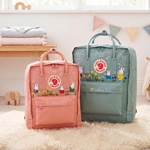 Könnte beinhalten: Zwei Fjällräven Kånken Rucksäcke in Rosa und Salbeigrün, jeweils mit gestickten Miffy-Figuren, Blumen und Sternbildern. Beide Taschen haben eine Fronttasche mit Reißverschluss, dem gestickten Namen Darlene M.B. und einem runden Logo.