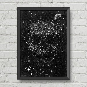 May include: A framed black and white print depicting a starry night sky with a crescent moon. The artwork features a dense cluster of bright stars and scattered smaller stars, creating a celestial theme. The frame is black, and the background is a dark, textured surface.