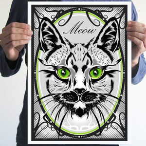 Puede incluir: Ilustraci&oacute;n en blanco y negro de la cara de un gato con ojos verdes, enmarcada en un marco decorativo con la palabra "Meow" en una fuente estilizada.