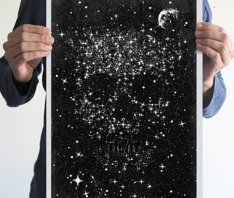 May include: Black and white art print depicting a starry night sky with a crescent moon. The artwork features a dense cluster of stars and a scattering of smaller stars against a dark background. The print is held by a person.