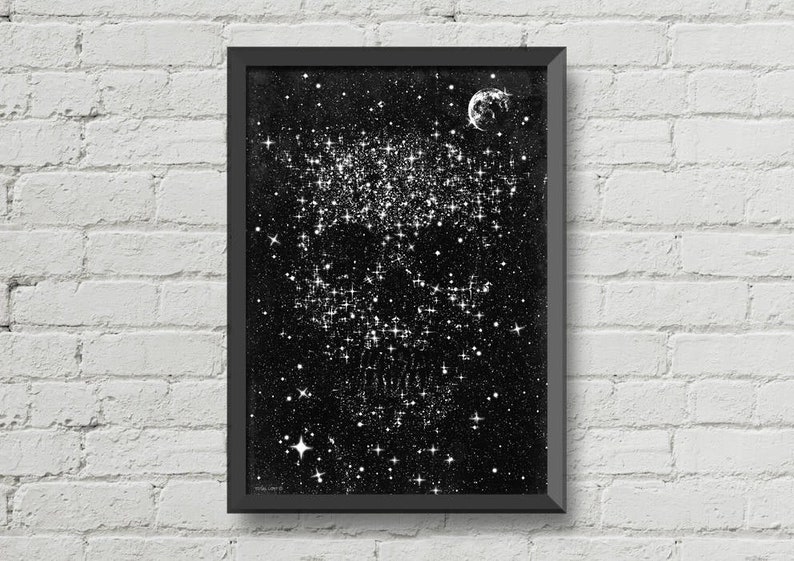 May include: A framed black and white print depicting a starry night sky with a crescent moon. The artwork features a dense cluster of bright stars and scattered smaller stars, creating a celestial theme. The frame is black, and the background is a dark, textured surface.
