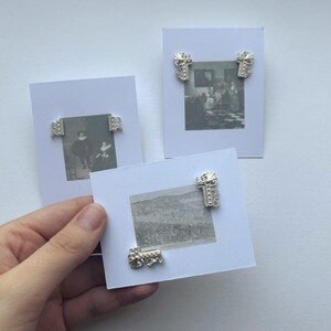 Puede incluir: Tres pequeñas impresiones artísticas enmarcadas con detalles decorativos plateados en las esquinas. Las impresiones presentan imágenes en blanco y negro de paisajes y figuras históricas. Los marcos están sobre un fondo blanco.