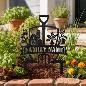 May include: A black metal garden stake featuring a shovel and pitchfork silhouette. The design includes a barn, silo, tomato plant, and pepper plant. A central banner displays the text [FAMILY NAME] in a bold, capitalized font style.