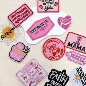 Peut inclure: Une collection d'écussons brodés de formes et de couleurs variées, présentant des textes tels que 'Well-Behaved Women Rarely Make History', 'God is Good', 'Expensive and difficult', 'I'm literally just a girl', 'MAMA' et 'God is within her'.