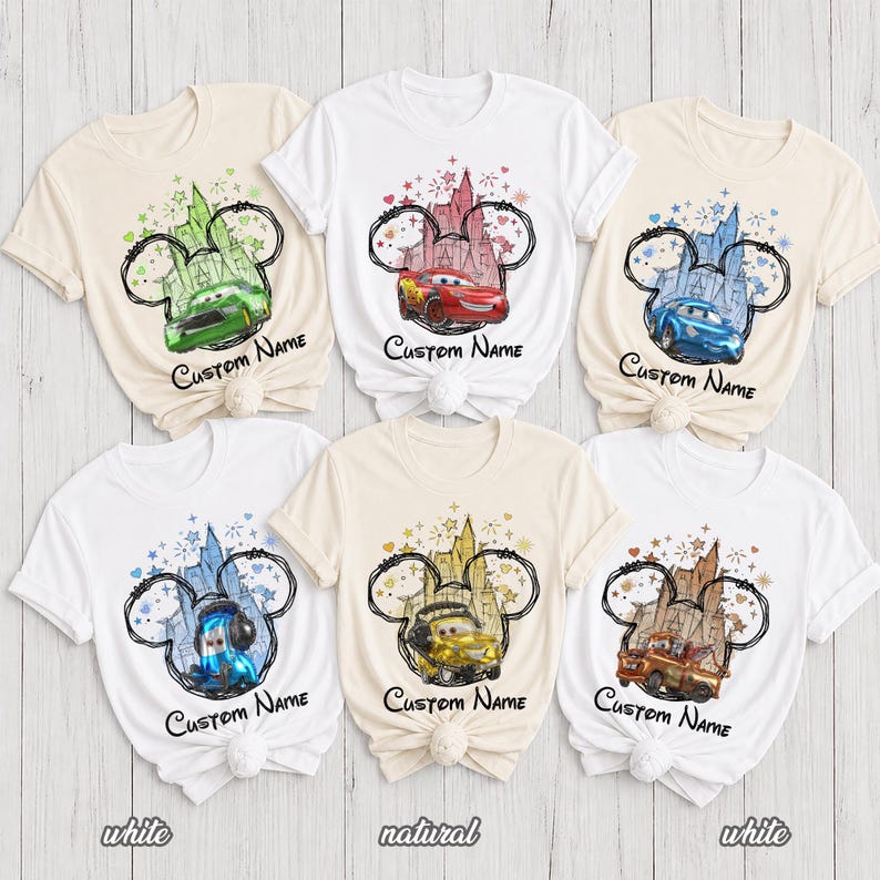 K&ouml;nnte beinhalten: Sechs kurz&auml;rmelige T-Shirts in Wei&szlig; und Naturfarben, jedes mit einer Grafik eines Disney Cars-Charakters in einer Micky-Maus-Ohren-Silhouette mit Schloss-Hintergrund, bunten Sternen und dem unter dem Design gedruckten Text Custom Name.