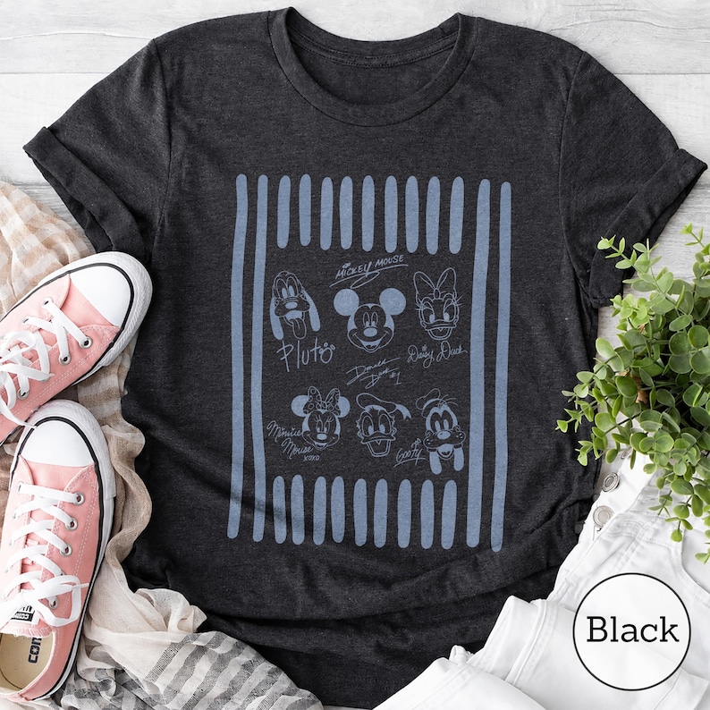 May include: A charcoal gray short-sleeve t-shirt featuring a light blue graphic print of Disney character faces including Mickey Mouse, Minnie Mouse, Donald Duck, Daisy Duck, Goofy, and Pluto, with their names written below each character.