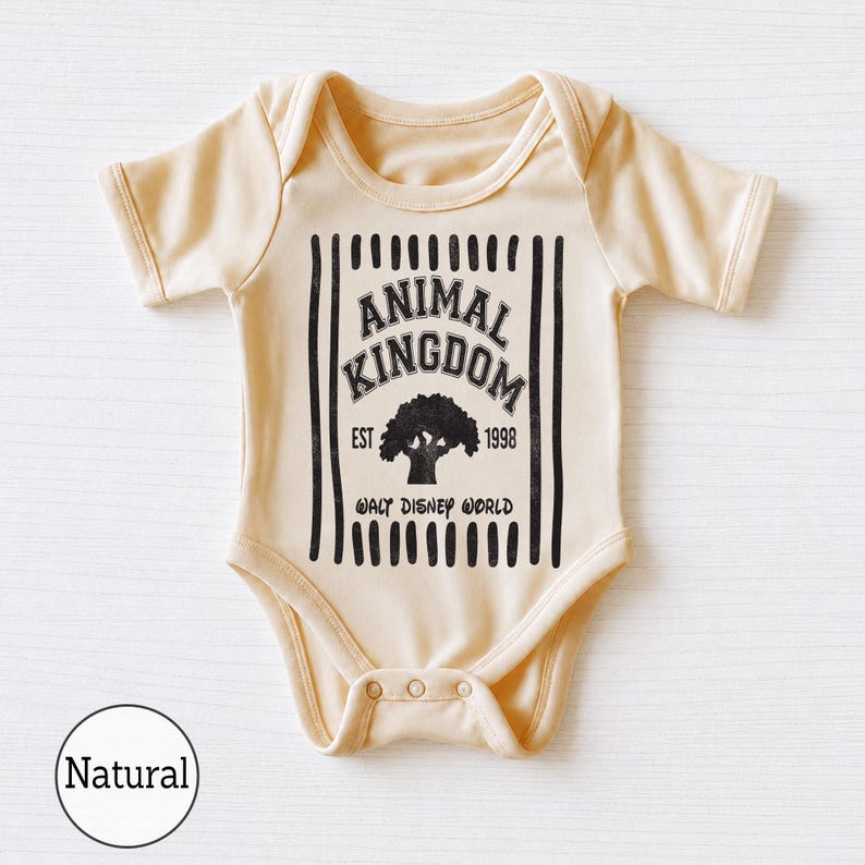 Pu&ograve; includere: Un body per neonati a maniche corte di colore naturale con una stampa grafica nera. Il design include strisce verticali, il testo ANIMAL KINGDOM, EST 1998 e WALT DISNEY WORLD, centrato attorno alla sagoma di un grande albero.