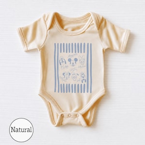 May include: A short-sleeved baby bodysuit in a light beige color. The center features a rectangular graphic with vertical blue stripes and line-art illustrations of Disney characters including Mickey Mouse, Minnie Mouse, Pluto, Donald Duck, and Daisy Duck.