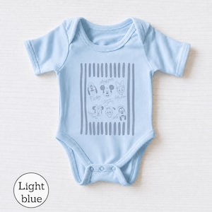 May include: A light blue baby bodysuit featuring short sleeves and a crew neckline. The center of the garment displays a gray graphic print of various Disney character faces and signatures framed by vertical stripes, including Mickey Mouse and Pluto.