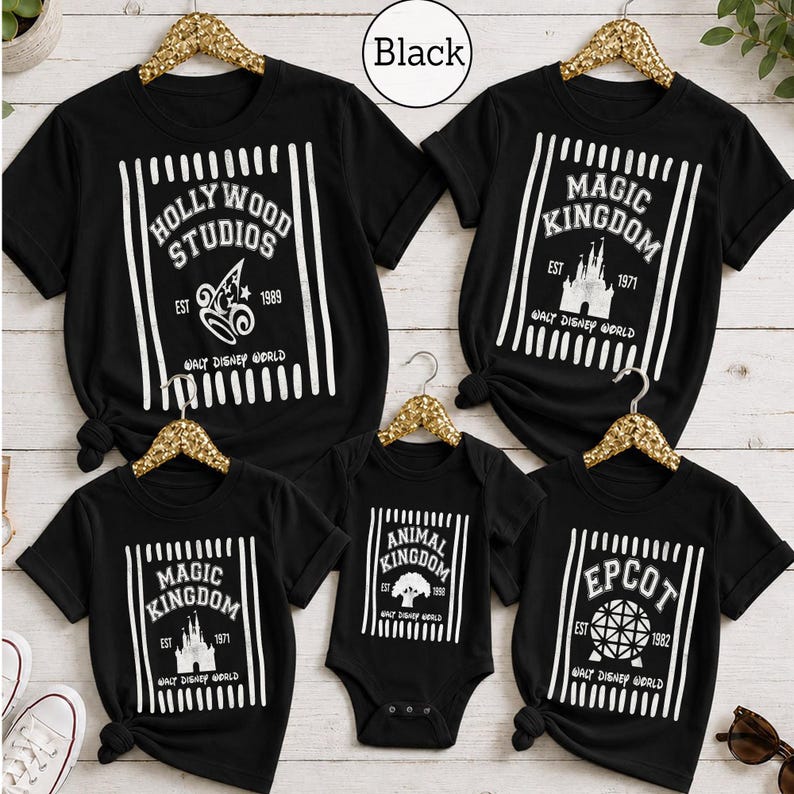 Pu&ograve; includere: Una collezione di cinque magliette nere a maniche corte e un body con stampe grafiche bianche dei parchi Walt Disney World. Ogni capo presenta strisce verticali, nomi dei parchi, anni di fondazione e simboli iconici come il castello e il globo.