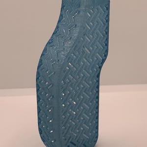 Könnte beinhalten: Ein durchscheinendes, hellblaues 3D-gedrucktes Objekt mit einer geschwungenen, länglichen Form und einem sich wiederholenden geometrischen Gittermuster auf der Oberfläche. Der obere Teil hat eine flache, rechteckige Öffnung und die Basis ist abgerundet.