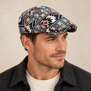 Puede incluir: Una gorra plana con un vibrante patrón tejido multicolor con formas geométricas en tonos negro, azul, rojo, amarillo y blanco. La gorra tiene una corona redondeada estructurada y una visera corta y rígida, mostrando un diseño textil detallado.