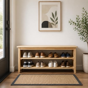 May include: A light-colored wooden shoe rack with two shelves, holding various pairs of shoes. A framed abstract art piece hangs above the rack. A woven rug with a dark border sits on the floor.