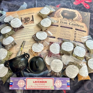 Puede incluir: Un caldero de hierro fundido negro con tapa, una caja de incienso de lavanda Satya y numerosas bolsas de plástico transparente pequeñas con diversas hierbas y especias secas, acompañadas de dos hojas de instrucciones Cauldron Magick.