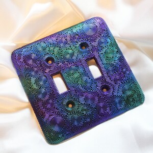 May include: A purple, green, and blue iridescent light switch cover with a swirling pattern.