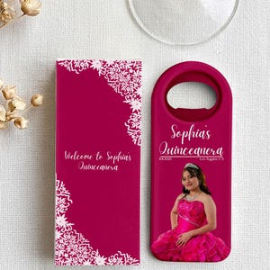 Peut inclure: Un décapsuleur magenta et une boîte rectangulaire assortie avec des motifs floraux blancs en dentelle. Les objets portent l'inscription "Welcome to Sophia's Quinceanera" et "Sophia's Quinceanera" ainsi qu'une photo d'une personne en robe rose.