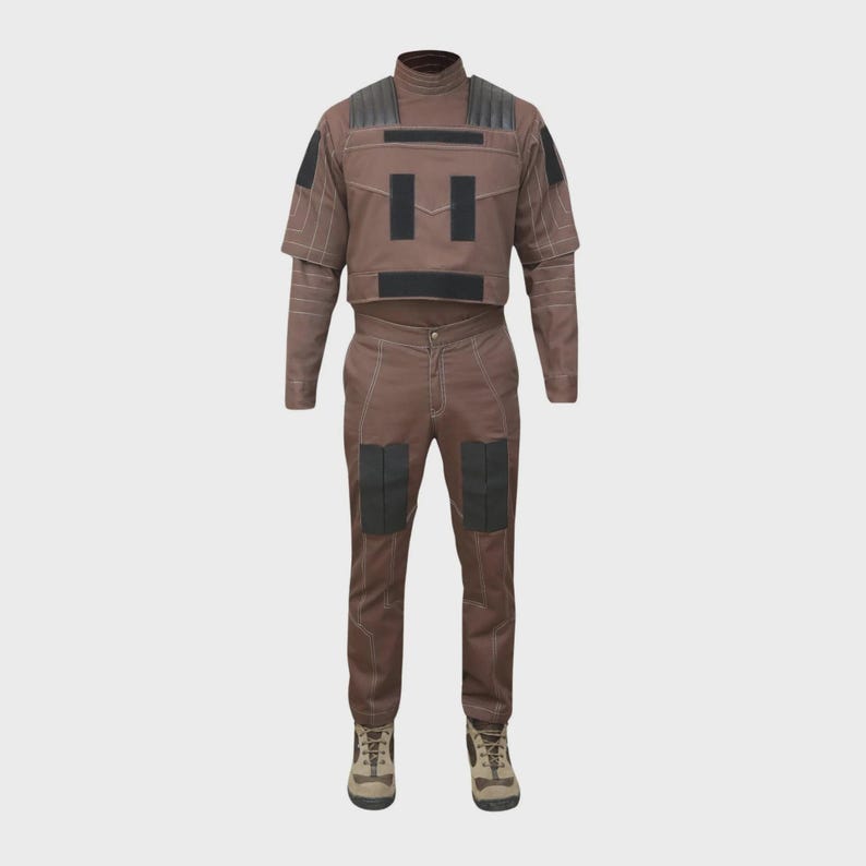 May include: A brown two-piece outfit consisting of a short-sleeved top and matching trousers. The top features black rectangular patches on the chest and shoulders. The trousers have black knee patches and white contrast stitching throughout.