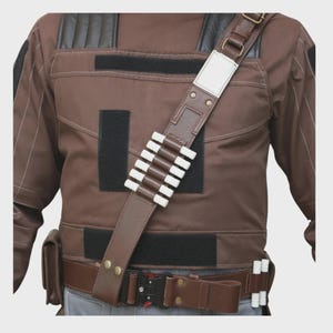 May include: A brown tactical vest featuring black shoulder panels, multiple black velcro patches, and a diagonal brown shoulder strap with six white cylindrical holders. A brown utility belt with a black metal buckle and two white holders.