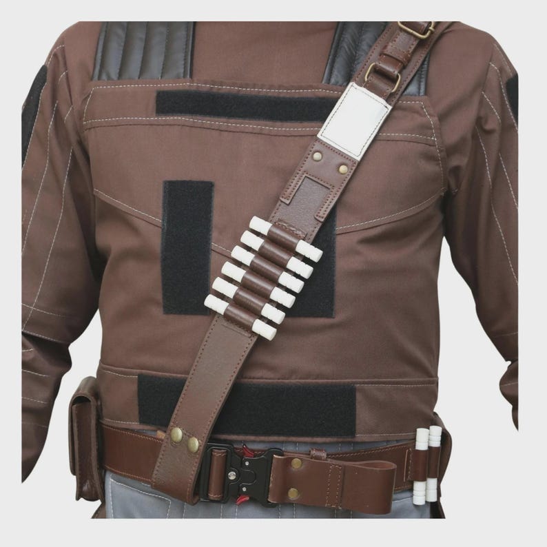 May include: A brown tactical vest featuring black shoulder panels, multiple black velcro patches, and a diagonal brown shoulder strap with six white cylindrical holders. A brown utility belt with a black metal buckle and two white holders.