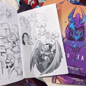 May include: Comic book with open pages showing black and white sketches of robots and characters. The cover on the right features a purple robot with the title "SO FAR".