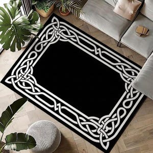 May include: A rectangular area rug featuring a solid black center surrounded by a wide, white border decorated with an intricate, continuous Celtic knotwork pattern that forms a frame around the entire perimeter of the floor covering.