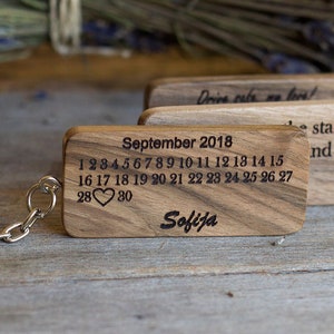 May include: Wooden keychain with a calendar for September 2018, the numbers 28 and 30 are highlighted with a heart symbol. The text "Sofija" is engraved below the calendar. The keychain also has a small wooden tag with the text "Drive safe my love!" and another tag with the text "The stars and".