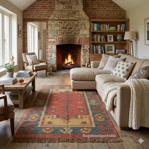 May include: A rectangular area rug featuring a central terracotta red field with a geometric pattern in yellow, blue, and dark brown. The rug has a wide blue border with repeating motifs and a fringed edge, displayed on a wooden floor.