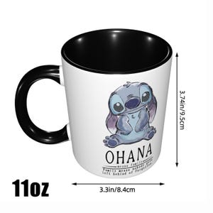 K&ouml;nnte beinhalten: Ein wei&szlig;er Keramikbecher mit schwarzem Innenraum und Henkel, verziert mit einer blauen Alien-Figur und dem Text OHANA means family. Family means nobody gets left behind or forgotten. Er ist 9,5 cm hoch und 8,4 cm breit.