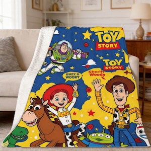 May include: A plush throw blanket featuring a vibrant blue and yellow background with Toy Story characters including Buzz Lightyear, Sheriff Woody, Jessie, Bullseye, Rex, and an alien. The text Toy Story and Sheriff Woody is printed on the fabric.