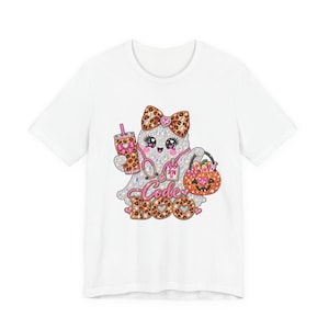 Può includere: Una t-shirt bianca con la grafica di un fantasma scintillante che indossa un fiocco leopardato, uno stetoscopio rosa e un badge RN. Il fantasma tiene in mano un bicchiere leopardato e un secchiello a forma di zucca. Il testo Code BOO è stampato.