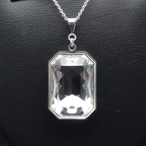 May include: A silver chain necklace with a large, clear, rectangular crystal pendant.