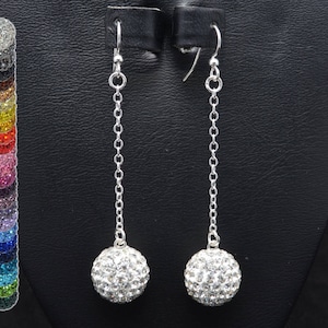 May include: A pair of silver dangle earrings with a clear crystal ball at the end of each earring.